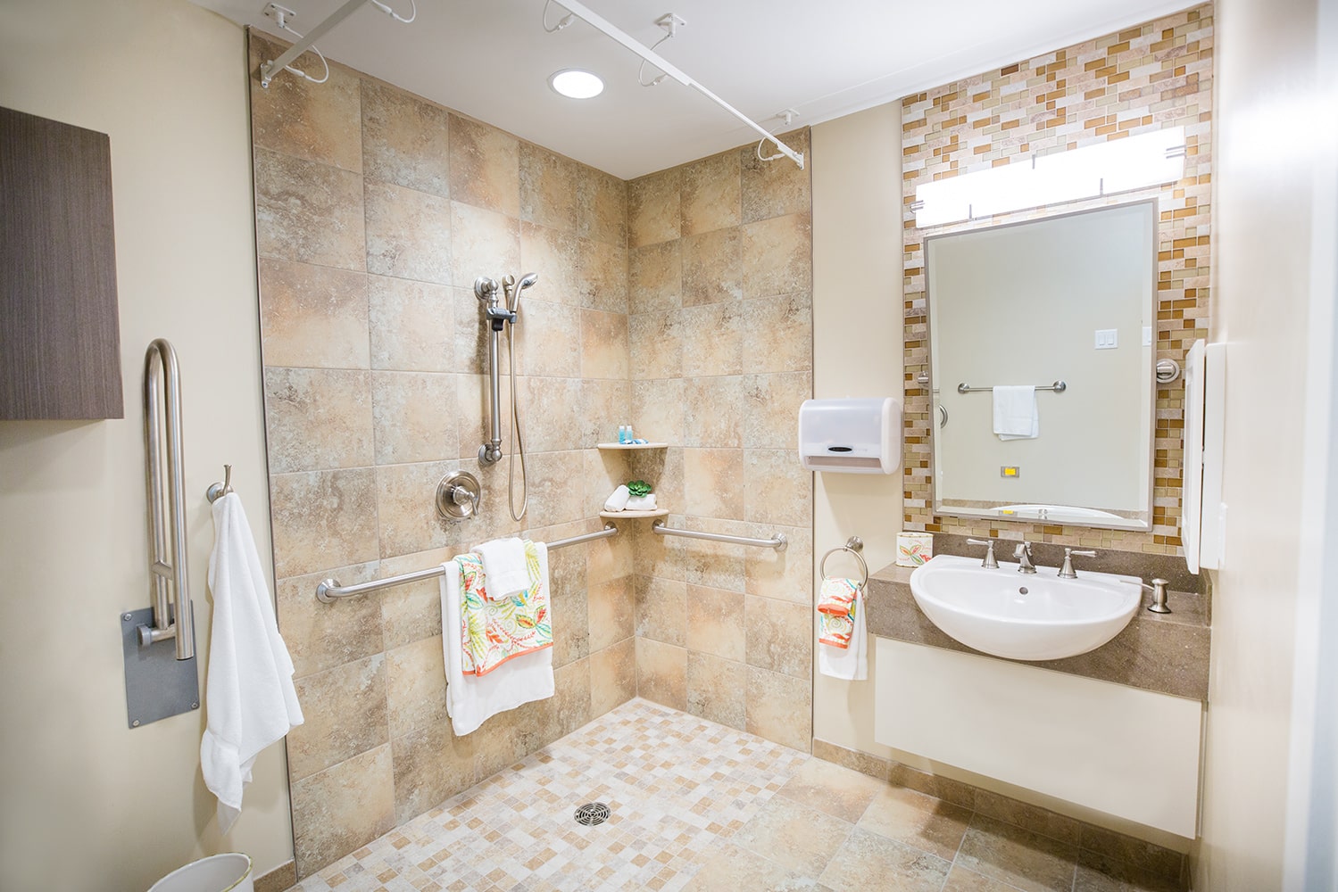 Bathroom with a shower and sink with brown tiles and grab bars in the shower