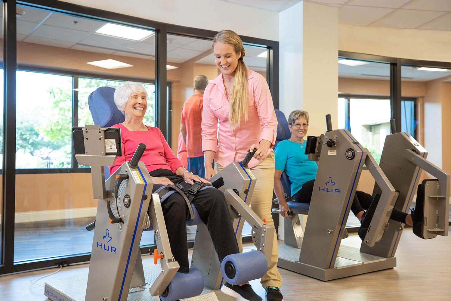 Trainer assisting woman working out with a leg lift fitness machine