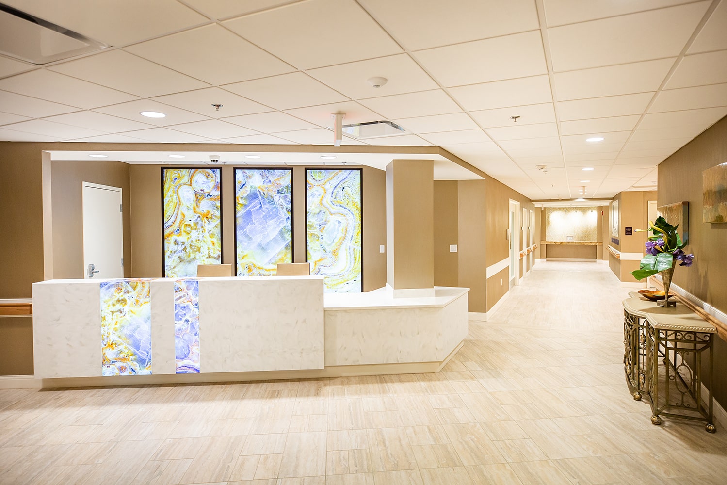 Clean and light front desk area of rehab facility with a large marble desk and abstract art hanging on the walls