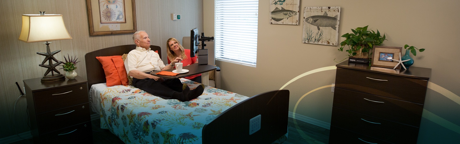 Man sitting in bed looking at a computer screen on a movable desk with woman by his side