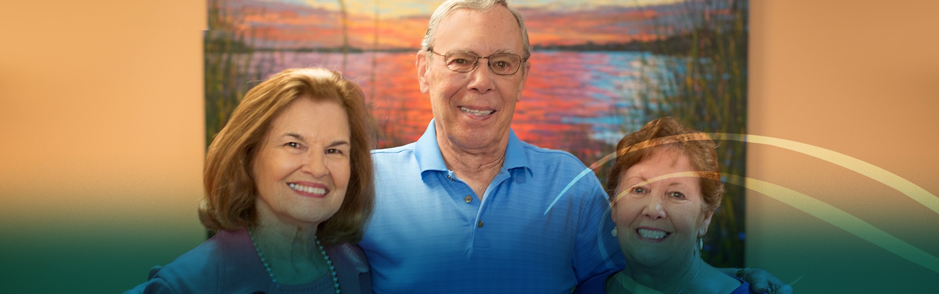 Man and two women smiling at the camera with abstract and colorful painting in the background